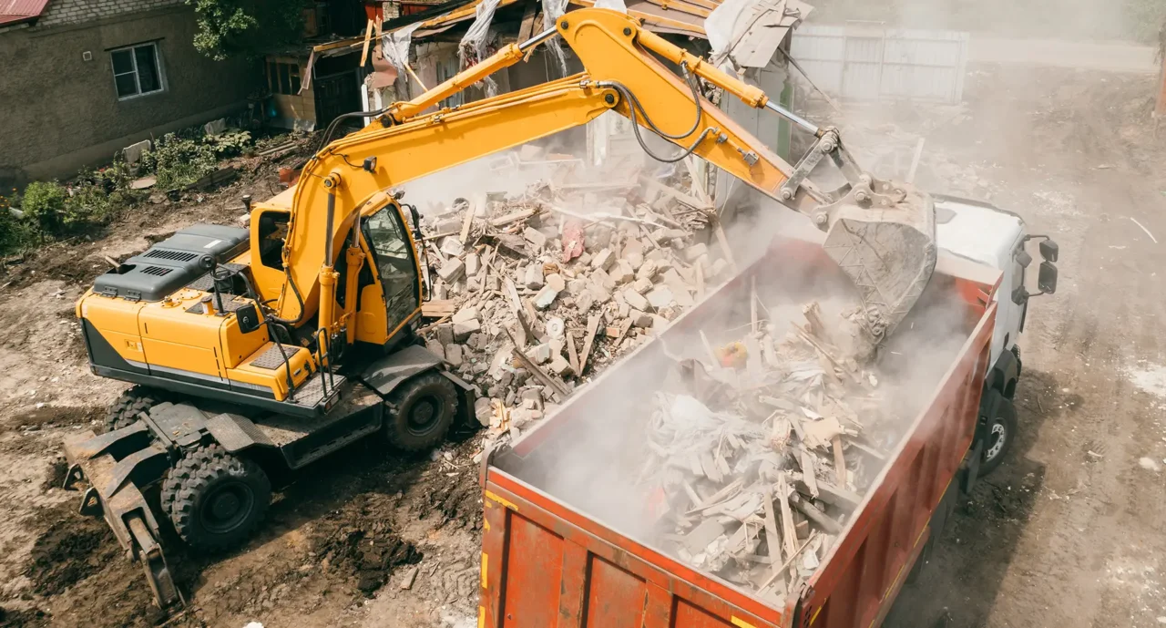 Digger pouring rubble into the back of a lorry