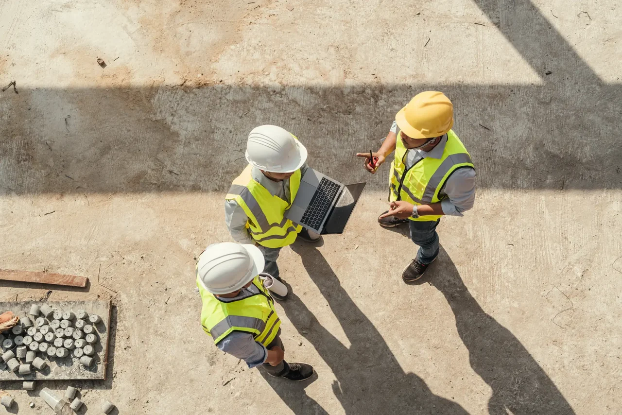 Three people on a construction site having talking.